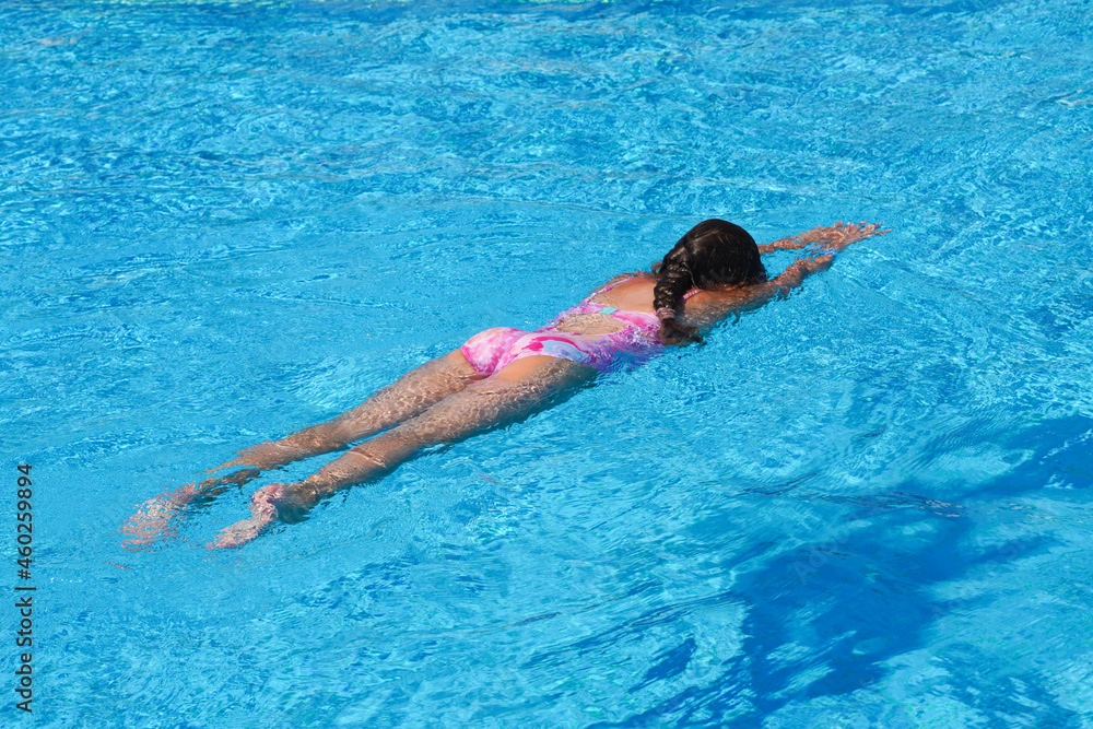 Little girl at swimming pool. Girl having fun swimming pool on summer vacation. Swimming girl.