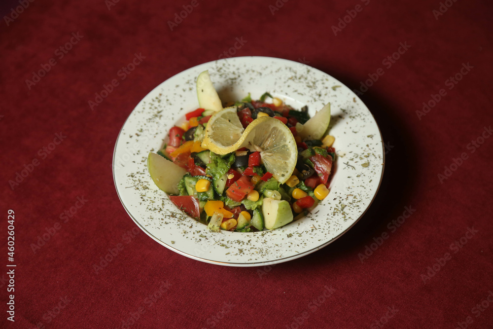 Vegetable salad with tuna in a red plate over dark blue slate, stone or concrete background. Top view with copy space. Vegetable salad with tuna in a red plate over dark blue slate, stone or concrete background. Top view with copy space.