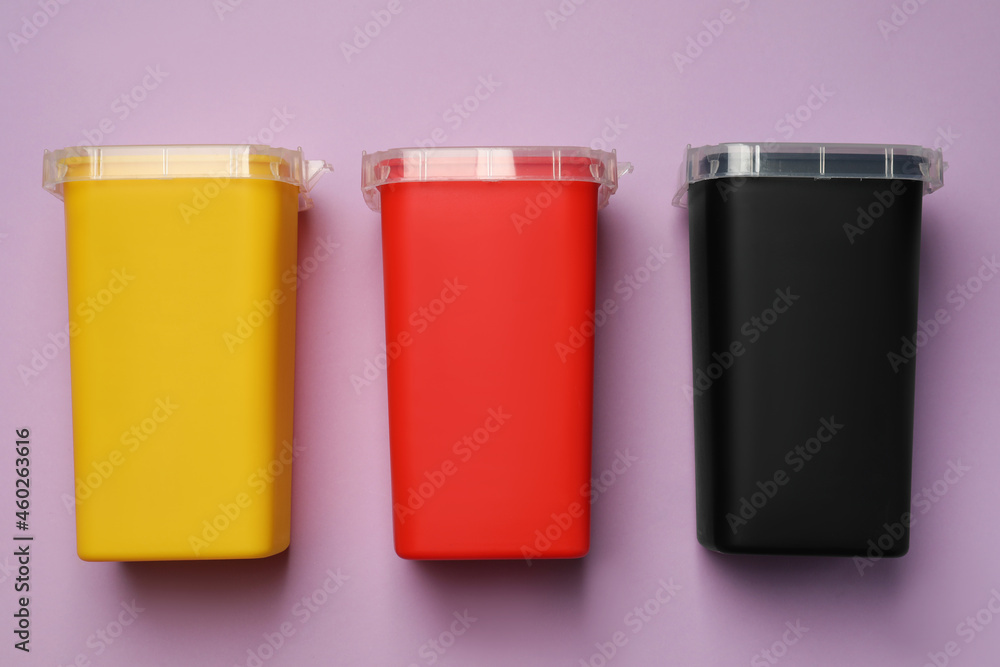 Sharps containers for used syringe on violet background, flat lay Sharps containers for used syringe on violet background, flat lay