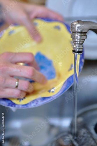 housewife washing dishes in the kitchen sink after the meal. cleaning and housework concept
