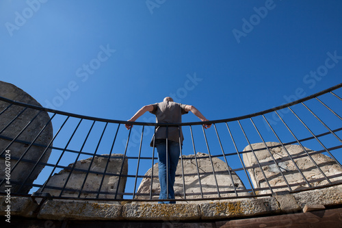 Man leaning against metal railing. Blue sky in the background, perspective. © AP-STUDIO