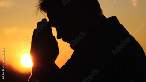 man prays at sunset in the sky, religious belief, the life of a believer, ramadan in the rays of the light of the sun, ask for forgiveness from the sky, read prayer in glare of sun, believe in dream photo