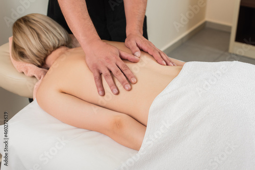 Masseur massaging back of woman on table in spa center