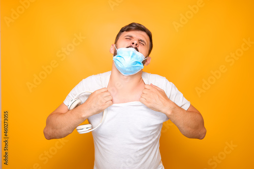 a man in a medical mask holds a white and musical headphones in his hands and gestures emotionally.
