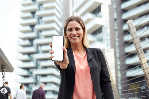 Smiling businesswoman holding blank screen's mobile in urban environment Free Download Smiling businesswoman holding blank screen's mobile in urban environment - GFXLoad