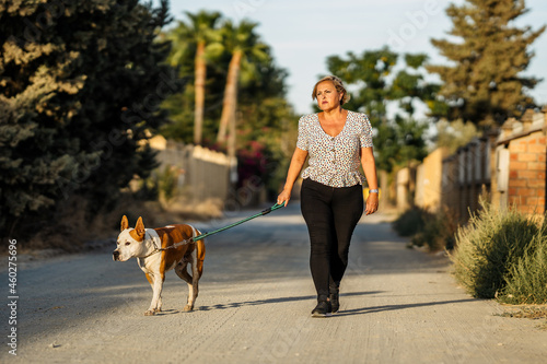 Woman walking a dog on an unpaved street