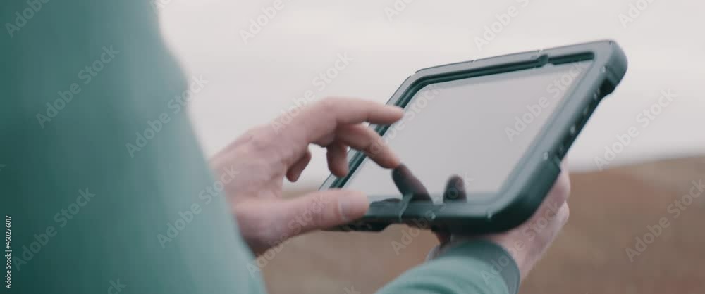 CU on hands, Caucasian male farmer using a tablet while standing in the field. Cloud technology for agriculture. Shot with 2x anamorphic lens CU on hands, Caucasian male farmer using a tablet while standing in the field. Cloud technology for agriculture. Shot with 2x anamorphic lens