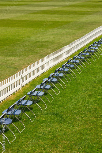 Row of chairs and fence on cricket ground