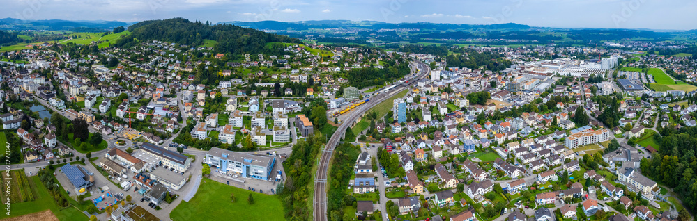 Aerial view of the city Oberuzwil with train passing by in Switzerland on a overcast day in summer.	