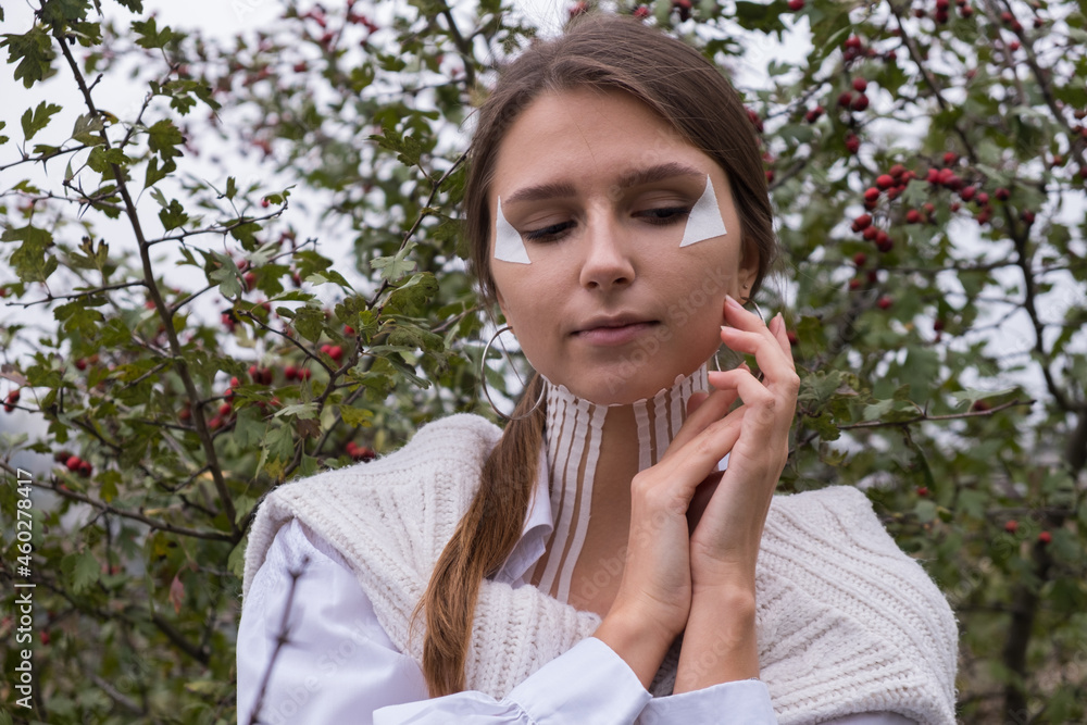 Face and body taping. A special cosmetic procedure for the skin. Beautiful young girl in autumn on the nature Face and body taping. A special cosmetic procedure for the skin. Beautiful young girl in autumn on the nature