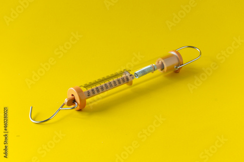 Fotografija Compact spring balancer with hook Isolated on yellow background.