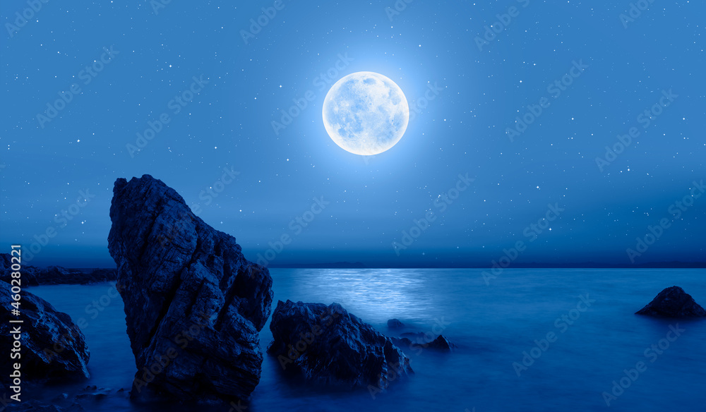 Fantastic landscape with strange stones in the sea -  Night sky with moon in the clouds  