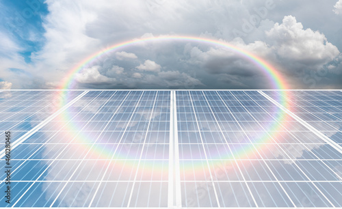 Close-up solar panel solar photovoltaic on stormy cloudy sky background with amazing round shaped rainbow - clean alternative electric energy concept.