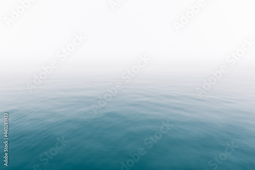 Heavy fog over calm ocean water surface - soft misty scenery on the sea with subtle ripples - Infinity - Calmness - serenity - lonely - quiet - moody background copy space