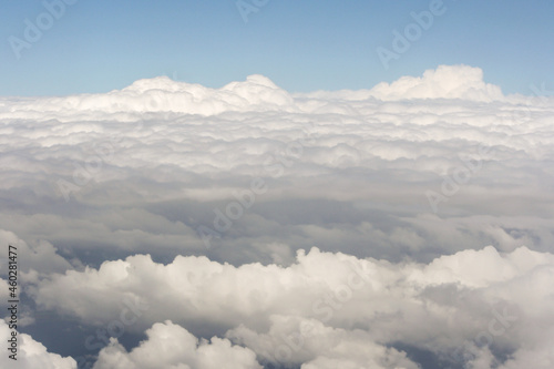View of above clouds from airplane window with blue sky background. Use for wallpaper or backdrop.