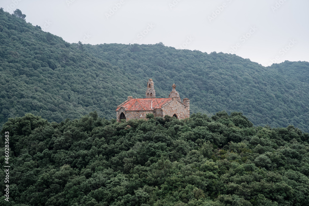 small church on top of mount with forest around and cloudy day catalonia, spain