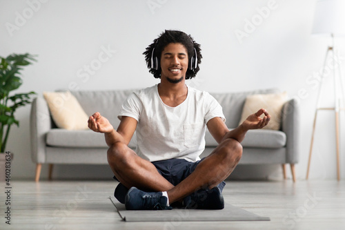 Meditation Concept. Calm Black Guy In Wireless Headphone Meditating At Home