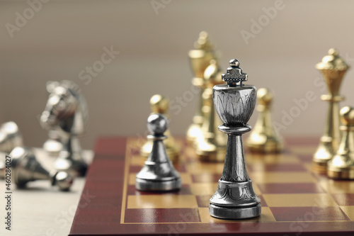 Chessboard with game pieces on beige background  closeup. Space for text
