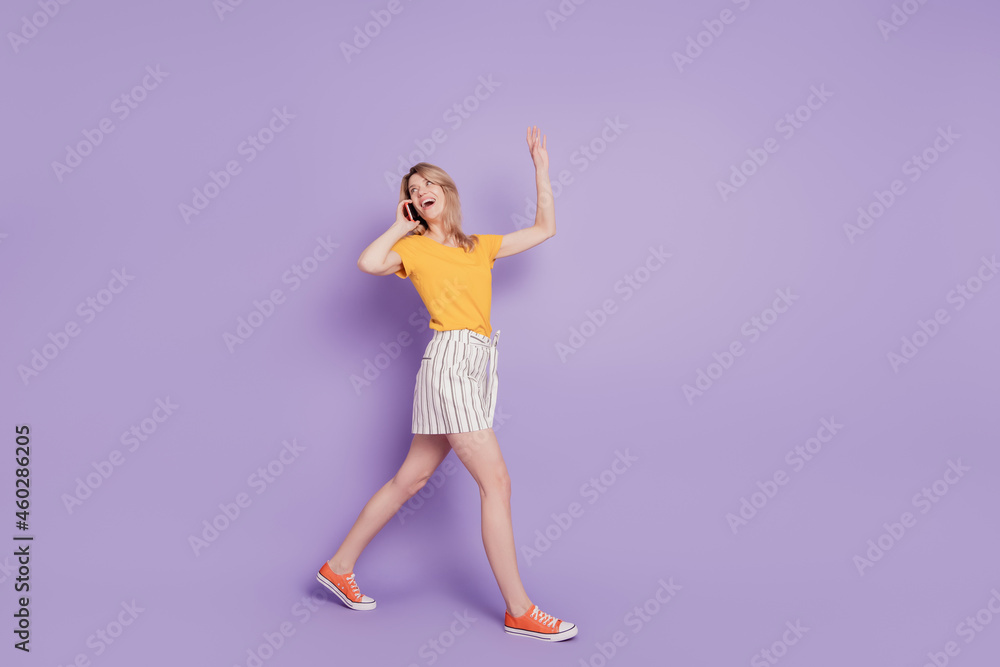 Photo of surprised girl talking on phone isolated on violet background