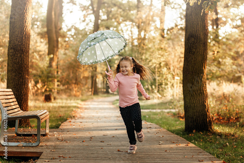 a little girl runs with an umbrella in her hands