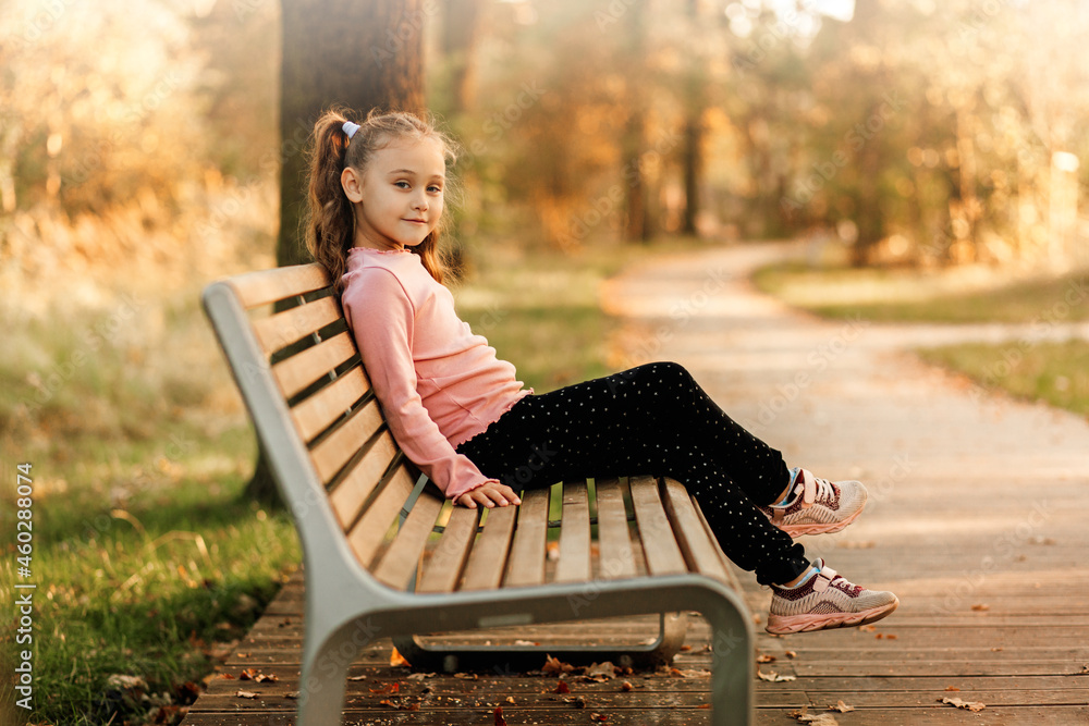 Little pretty girl sits on a bench in the park in the autumn Stock ...