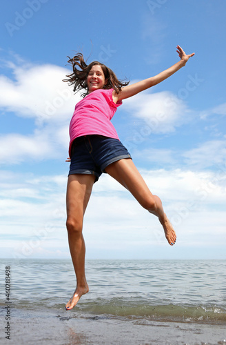 jump of a happy girl on the seashore in summer symbol of carefree joy
