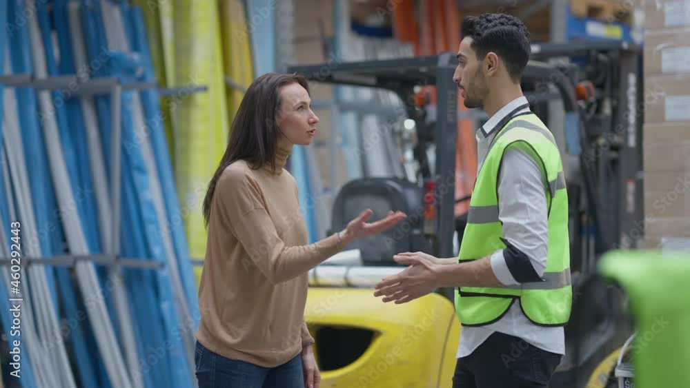 Anxious nervous man and woman arguing in industrial warehouse yelling and gesturing. Troubled Caucasian woman and Middle Eastern man discussing shipping failures in storage indoors Anxious nervous man and woman arguing in industrial warehouse yelling and gesturing. Troubled Caucasian woman and Middle Eastern man discussing shipping failures in storage indoors