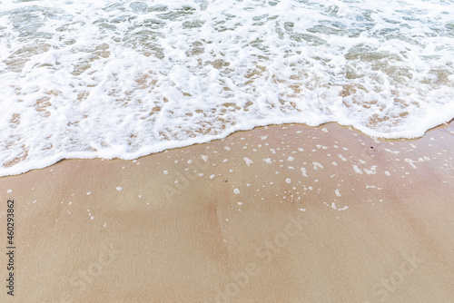 Wave of the sea on sandy beach white foam.Top view of a wave breaking on the sand at the beach. Top view,Copy space.