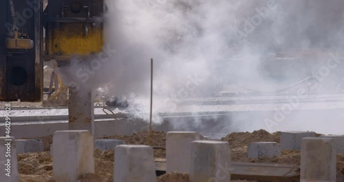 Excavation at a construction site, pile driving machine with rumble and smoke drives piles deep into the ground to ensure the strength of the foundation of the future structure 