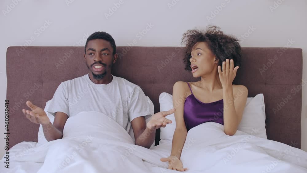 Offended man and woman arguing in bed, couple having relationship problems Offended man and woman arguing in bed, couple having relationship problems