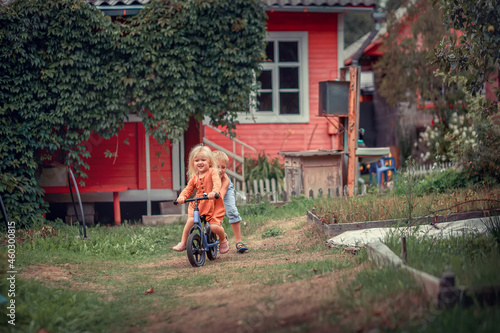 A brother is riding his little sister on a bicycle in the country. Image with selective focus and toning