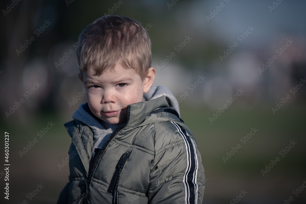 Niño rubio con campera jugando en el parque en invierno Niño rubio con campera jugando en el parque en invierno