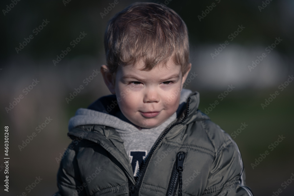 Niño rubio con campera jugando en el parque en invierno Niño rubio con campera jugando en el parque en invierno