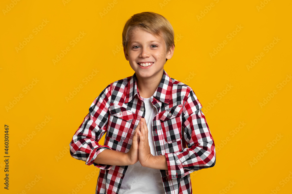 Smiling european adolescent boy modern student holds hands pressed together, prays as good mark and exam result Smiling european adolescent boy modern student holds hands pressed together, prays as good mark and exam result