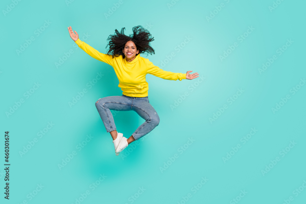 Full length body size view of pretty cheerful girl jumping fooling having fun isolated over bright teal turquoise color background Full length body size view of pretty cheerful girl jumping fooling having fun isolated over bright teal turquoise color background