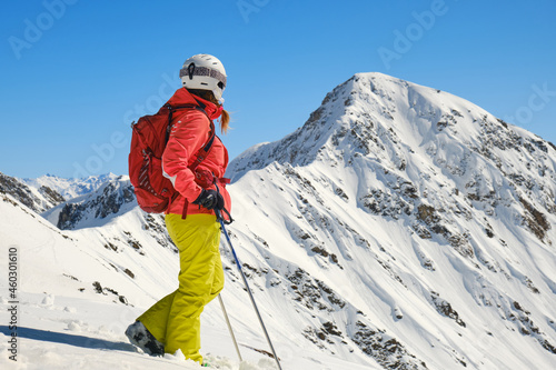 Woman with backpack, helmet, and ski poles looks towards Parpaner Rothorn peak and ridge. Breathtaking views in Arosa Lenzerheide resort, Switzerland. Space for text, copy space. 