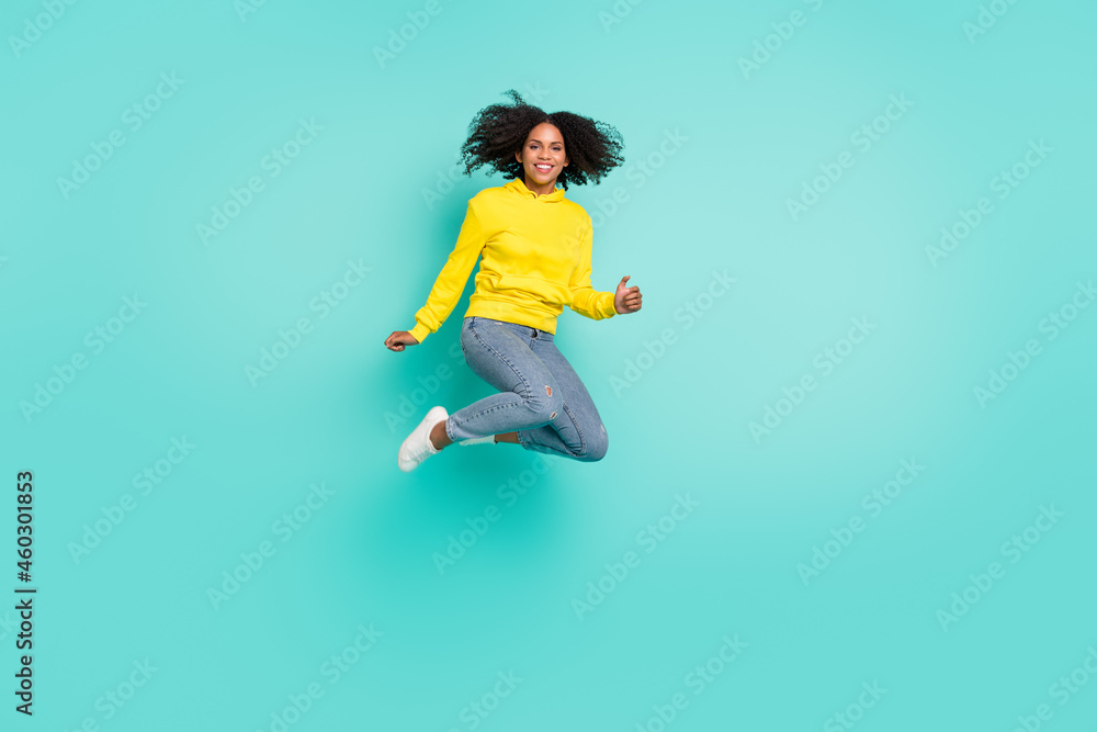 Full length body size view of attractive cheerful carefree girl jumping isolated over bright teal turquoise color background Full length body size view of attractive cheerful carefree girl jumping isolated over bright teal turquoise color background