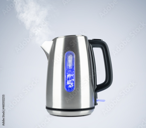 Boiling steel electric kettle with lights and steam on light gray background. File contains a path to isolation.