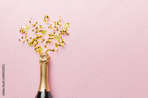 Creative flat lay composition with bottle of champagne and space for text on color background. Champagne bottle with colorful party streamers. holiday or christmas concept