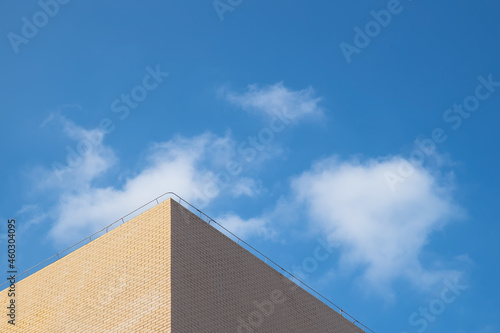 Part of the light yellow building under the blue sky and white clouds