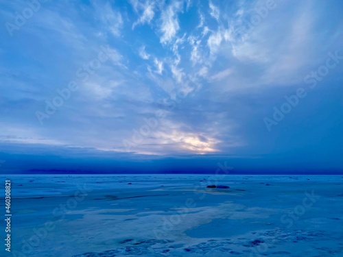 winter landscape in blue, the sun appears through the clouds