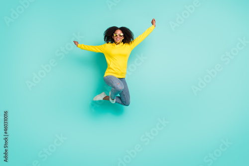 Full length body size view of nice cheerful wavy-haired girl jumping having fun isolated over bright teal turquoise color background