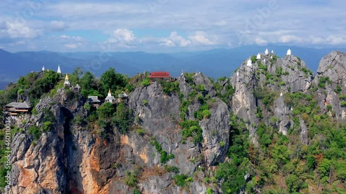 White pagoda and stupa on top of mountain cliff in woodland called Wat Phra Bat Pupha Daeng temple, Chae Home, Lampang province, Thailand. photo