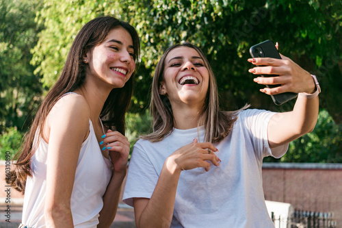 Girlfriends taking selfie on smartphone in park photo