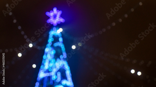 Christmas holiday background. Christmas tree in shining garland in blur.