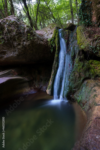 waterfall in the middle of the forest falling into a rocky natural pool  gorg de la sort aiguafreda catalonia  spain