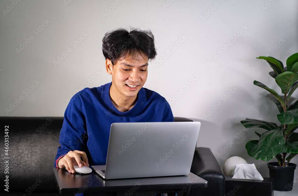 young man using laptop computer, typing on keyboard, writing email or message, chatting, shopping, lerning, successful freelancer working online on computer, sitting in modern living room at home. young man using laptop computer, typing on keyboard, writing email or message, chatting, shopping, lerning, successful freelancer working online on computer, sitting in modern living room at home.