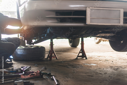 Male mechanic repairing suspension system of car in garage