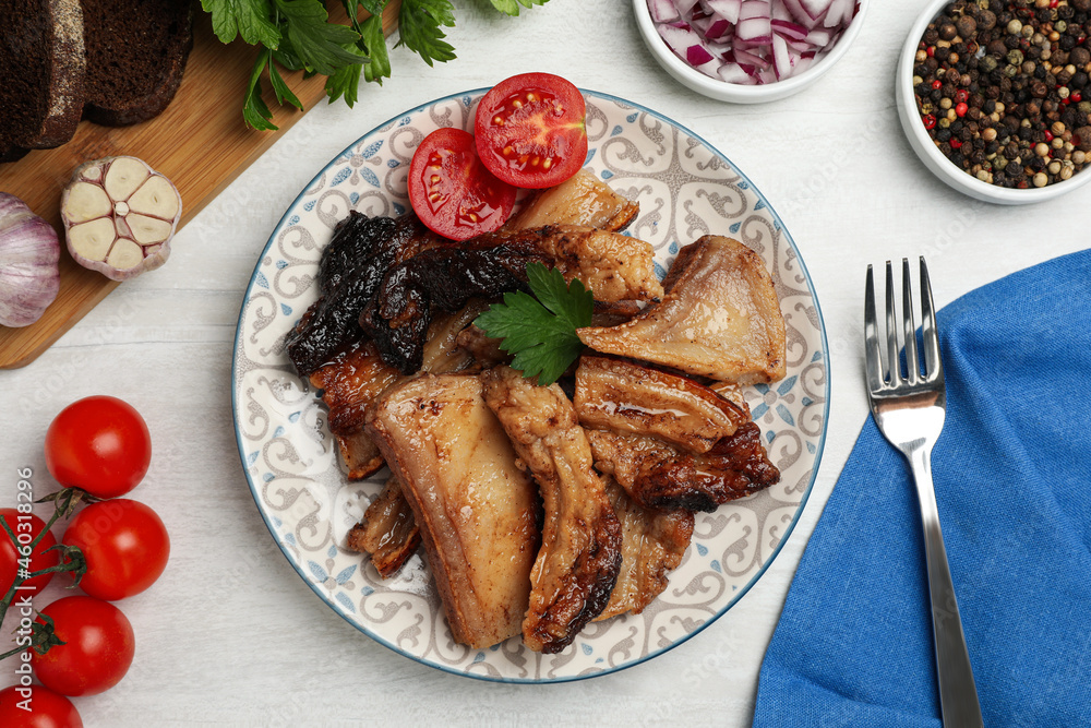 Tasty fried pork lard with parsley and tomatoes on white wooden table, flat lay Tasty fried pork lard with parsley and tomatoes on white wooden table, flat lay
