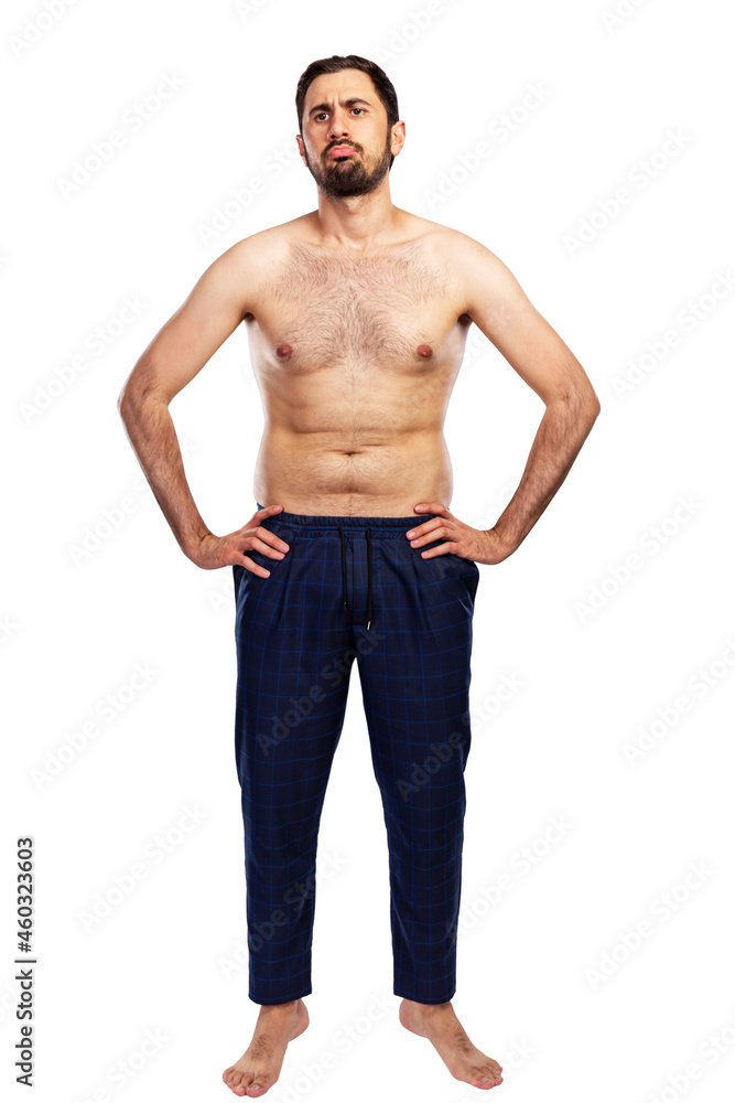 A frustrated man stands in trousers with a naked torso. Unsportsmanlike figure. Full height. Isolated on white background. Vertical. A frustrated man stands in trousers with a naked torso. Unsportsmanlike figure. Full height. Isolated on white background. Vertical.